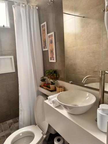 a bathroom with a white toilet and a sink at La Estância Flats in Iguape