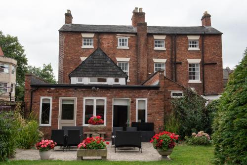 a large red brick building with chairs and flowers at Abbots Mead Hotel in Shrewsbury