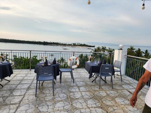 a patio with black tables and chairs and the water at Islandview Whitehouse - Camotes in Esperanza