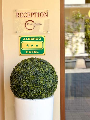 a sign on the side of a hotel with a bush at Hotel Rossovino Como in Como