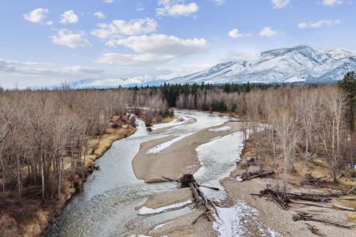 a river in a field with mountains in the background at Mara Luxury Cabins- Ponderosa in Hamilton