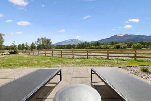 two benches on a patio with mountains in the background at Mara Luxury Cabins- Ponderosa in Hamilton