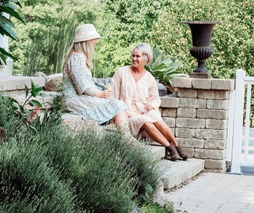 two women sitting on a stone wall in a garden at Cellar Suite at Winery and Vineyard in Waterford