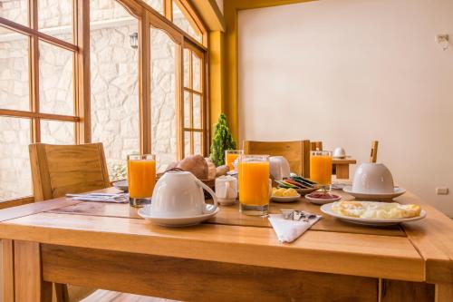 een houten tafel met borden eten en sinaasappelsap bij Hotel Suiza Peruana in Huaraz