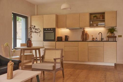 une cuisine avec des armoires en bois et une table avec des chaises dans l'établissement Yarn - Romy Deluxe Apartment, à Ballycastle