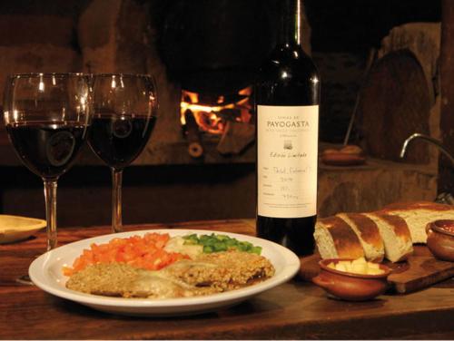 una mesa con un plato de comida y una botella de vino en Sala de Payogasta en Payogasta