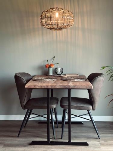 a dining room table with chairs and aendant light at Boerderijkamers Sniedershof in Deurningen