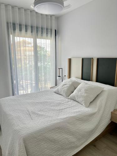 a white bed in a bedroom with a large window at Air-conditioned Elisa Apartment with spacious sunroof lounge and swimming pool in San Javier