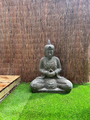 a statue sitting on the grass in front of a fence at La Floresta Suite in Sant Cugat del Vallès
