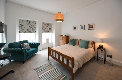 a bedroom with a bed and a green couch at Ayrbados - 4 bed townhouse in Ayr in Ayr