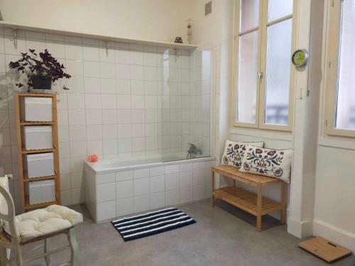 a bathroom with a tub and a table and a chair at Maison Bonhomme in Cusset
