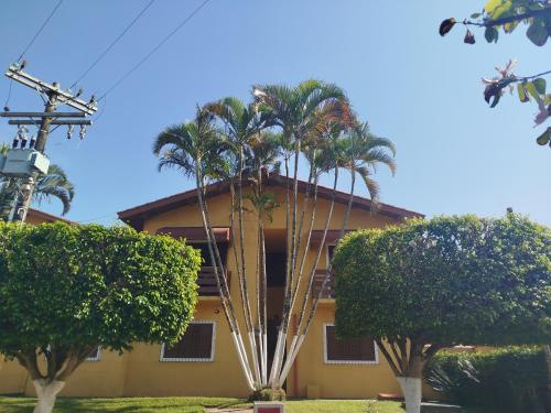 a house with palm trees in front of it at Hotel Xapuri in Peruíbe