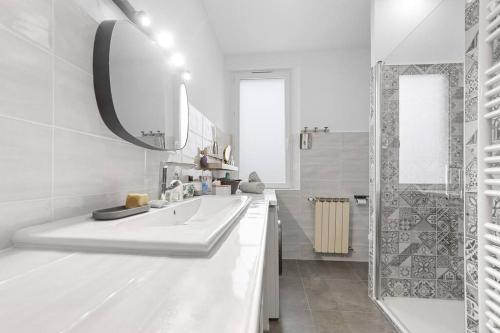 une salle de bain blanche avec un lavabo et un miroir dans l'établissement Superbe 120m2, proche centre, parking, à Saint-Raphaël