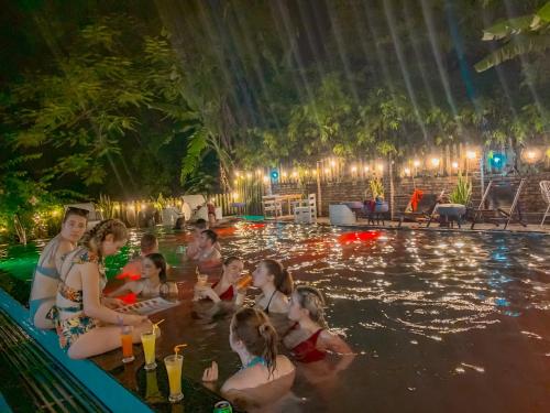 a group of people sitting in a swimming pool at night at Tam Coc Central Bungalow-Hostel in Vũ Lâm