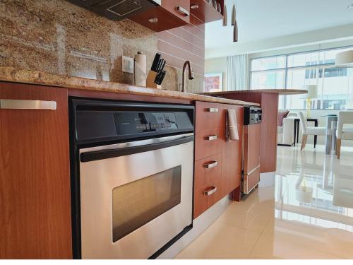 a kitchen with a stainless steel oven and wooden cabinets at Lux Aka Brickell Condo in Miami