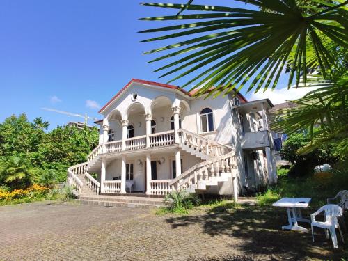 a large white house with a porch and stairs at Georginos house in Makhinjauri