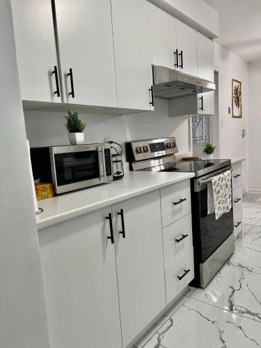 a white kitchen with white cabinets and a microwave at Private Room Near Airport K6 in Mississauga