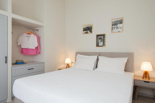 a bedroom with a white bed and a pink shirt hanging on the wall at Villa Grotta in Kamarai