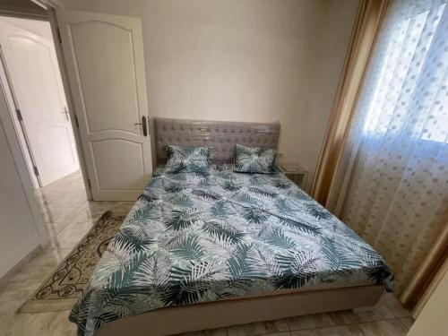 a bedroom with a bed with a blue and white comforter at location Saisonniere S2 a Sousse in Kasnadar