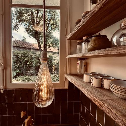 une ampoule suspendue dans une cuisine avec une fenêtre dans l'établissement Le NID DE CIERP, à Cierp