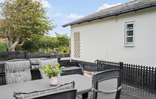 a patio table with chairs and a vase of flowers at 4 Bedroom Lovely Home In Lemvig in Lemvig
