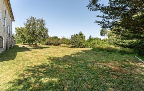 a field of grass next to a building with trees at Le Clos Montaugé in Virsac