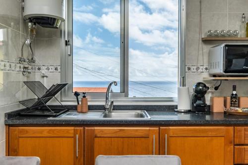 a kitchen with a sink and a large window at Basalto in Seixal