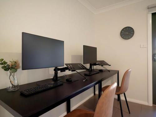 a desk with a computer and two monitors on it at Little Manhattan - Dubbo in Dubbo