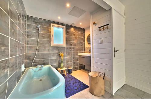 une salle de bain avec une baignoire et un lavabo dans l'établissement Casa Marcel déco sympa au calme dans la pinède, à La Tremblade