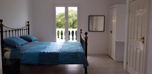 a bedroom with a bed with blue sheets and a window at Olive Villa in Episkopianá