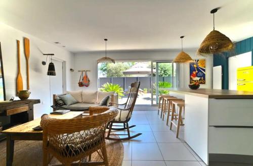 une cuisine et un salon avec une table et des chaises dans l'établissement Casa Marcel déco sympa au calme dans la pinède, à La Tremblade