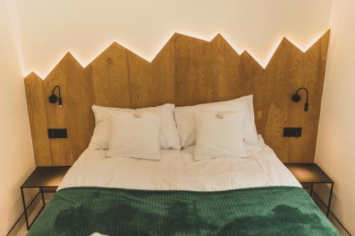 a bed with a wooden headboard and white pillows at Sowie Chatki - domki z widokiem na Góry Sowie in Sokolec
