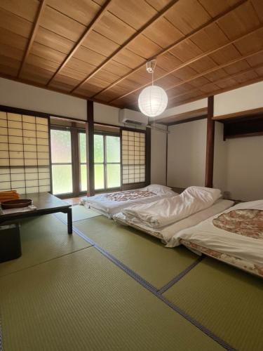 una stanza con due letti, un tavolo e finestre di WAY SHIRAKAWAGO - Private, Free Parking and Newly Opened 2022 WAY SHIRAKAWAGO a Shirakawa