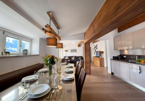 a dining room with a long table and a kitchen at Panoramic Penthouse 10 min to Zell am See & Kaprun in Piesendorf