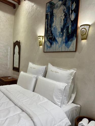a white bed with white pillows and a painting on the wall at Riad Safia in Rabat