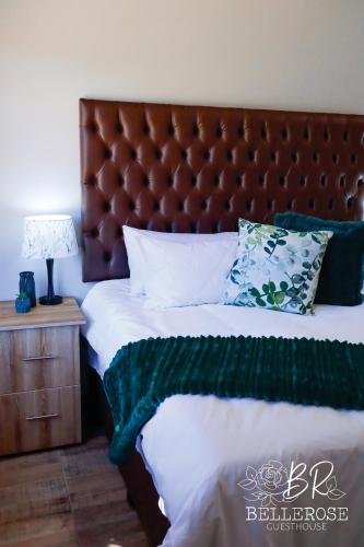 a bed with a brown headboard and a green blanket at Bellerose Guesthouse in Klerksdorp
