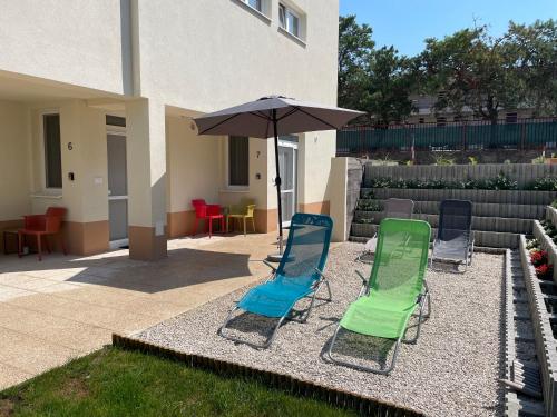 a group of lawn chairs and an umbrella at Apartmány Silvia in Dunajská Streda