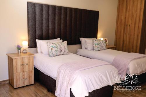 a bedroom with two beds and a headboard at Bellerose Guesthouse in Klerksdorp