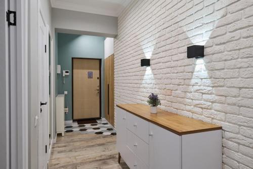 ein Badezimmer mit einer weißen Ziegelwand und einer Ablagefläche in der Unterkunft Роскошные Двухкомнатные Апартаменты in Almaty