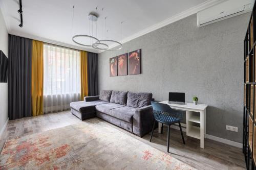 ein Wohnzimmer mit einem Sofa und einem Schreibtisch mit einem Laptop in der Unterkunft Роскошные Двухкомнатные Апартаменты in Almaty