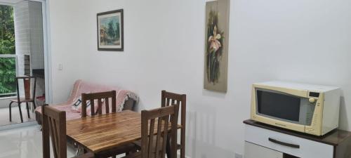 a dining room with a table and a tv at Apartamento lumier 109 in Ubatuba