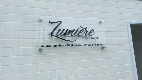 a sign on the side of a white tiled wall at Apartamento lumier 109 in Ubatuba