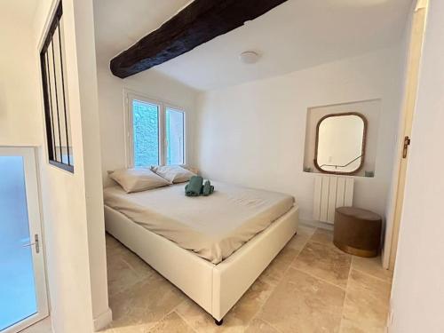 una camera da letto bianca con un letto e uno specchio di Maisonnette rénovée entre mer et montagne avec 4 couchages au cœur du village médiéval de Tourrettes sur loup proche st Paul de vence Grasse Gourdon Nice Cannes a Tourrettes-sur-Loup