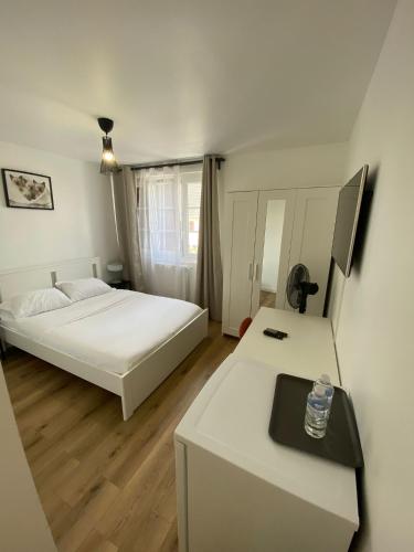 a bedroom with a white bed and a desk at G-Logement-Francilien Aéroport CDG, Parc des expositions Villepinte, Bourget, Astérix. in Goussainville