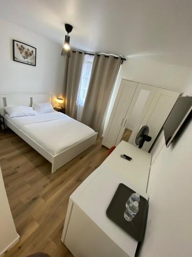 a room with two beds and a table with a desk at G-Logement-Francilien Aéroport CDG, Parc des expositions Villepinte, Bourget, Astérix. in Goussainville