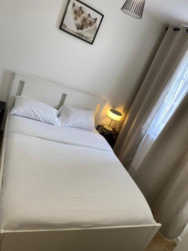 a white bed in a room with a window at G-Logement-Francilien Aéroport CDG, Parc des expositions Villepinte, Bourget, Astérix. in Goussainville
