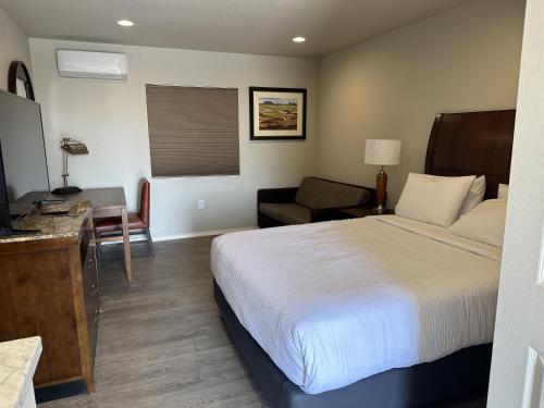 a hotel room with a bed and a chair and a desk at The GQ Extended Stay in George