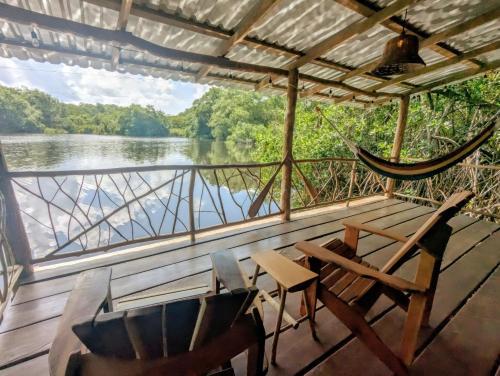 a hammock and chairs on a deck with a view of a river at La Isla Dulce in Lívingston