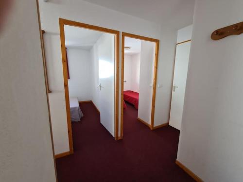 un couloir avec trois portes et un lit dans une chambre dans l'établissement T3 Les Cristallines, à Orcières