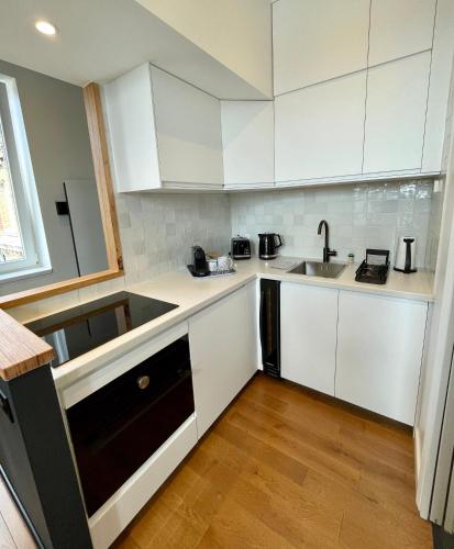 une cuisine avec des armoires blanches et un évier dans l'établissement Le Eight - Villa la Potinière - Moderne & Intime - Front de mer, à Dunkerque